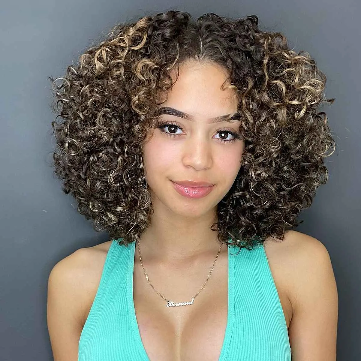 textured curly crop hairstyle with golden highlights